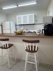 a kitchen with a counter with two bar stools at Casa em condominio na Praia de Juquehy in São Sebastião