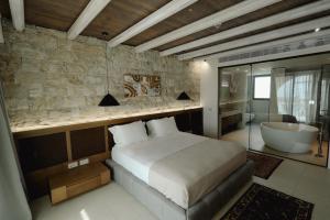 a bedroom with a bed and a tub and a bathroom at Drymades Inn Resort in Dhërmi