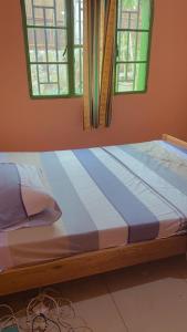 a bed in a room with two windows at Hostelito Room in Kigali