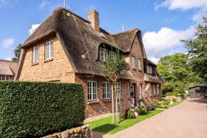 an old brick house with a thatched roof at Smuk Huus in Nieblum