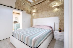 a bedroom with a bed and a stone wall at Dimora Donna Lucrezia in Mola di Bari