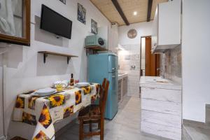 a kitchen with a table and a blue refrigerator at Dimora Donna Lucrezia in Mola di Bari