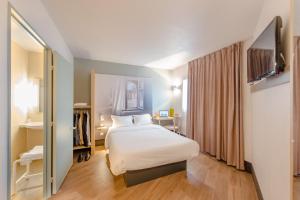 a hotel room with a bed and a desk at B&B HOTEL Blois in Vineuil