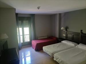 a hotel room with two beds and a window at Hotel Restaurante Ribera del Chicu in Arriondas