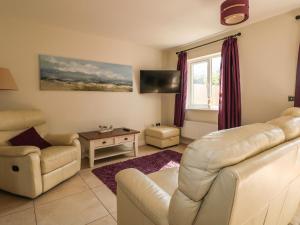 a living room with a couch and chairs and a tv at Pebble House in Worthing