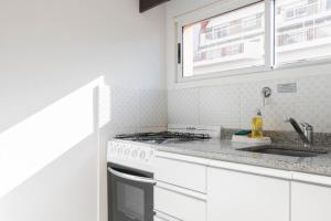 cocina blanca con fogones y fregadero en Lumimoso departamento en Buenos Aires 1 dorm en Buenos Aires
