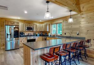 a kitchen with wooden cabinets and a large island with bar stools at Kingslanding Cabin in Carrabassett