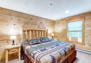 a bedroom with a bed and a wooden wall at Kingslanding Cabin in Carrabassett