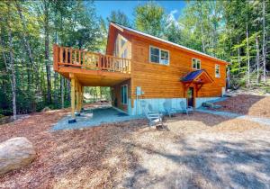 a cabin in the woods with a large deck at Kingslanding Cabin in Carrabassett