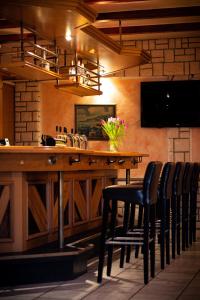 a bar with black chairs and a wooden table with flowers at Eggersheimer Hof in Nörvenich