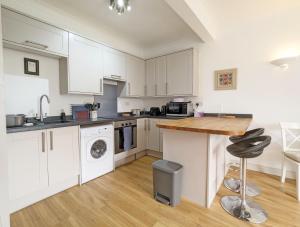 Una cocina con gabinetes blancos y una encimera de madera. en Emsdale House, en Emsworth