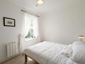 a white bedroom with a bed and a window at Emsdale House in Emsworth