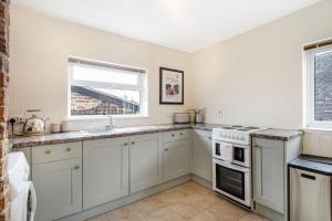 a kitchen with white cabinets and a sink and a window at Pass the Keys Cosy Countryside Cottage in Tonbridge +8 photos