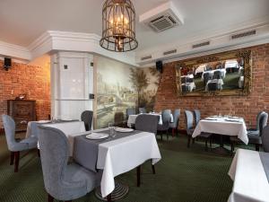 a restaurant with white tables and chairs and a brick wall at Akyan St.Petersburg in Saint Petersburg