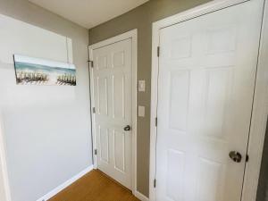 a hallway with a white door and a painting at Thames River Cottage in Uncasville