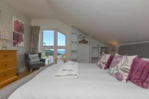 1 dormitorio con 1 cama blanca grande con almohadas rosas y moradas en 7 Sandy Lane, en St Ives