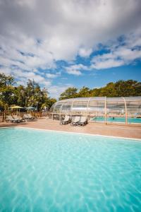 une piscine avec des chaises et un bâtiment dans l'établissement Les Maritimes, à Seignosse