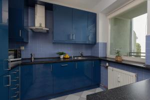 a blue kitchen with a sink and a window at Comfy Apartment Powstańców Śląskich by Renters in Warsaw