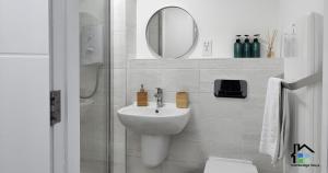 Baño blanco con lavabo y espejo en Cambridge Stays Riverside 1BR Flat-Walk to Centre-Parking, en Cambridge