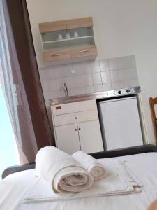 uma cozinha com um lavatório e toalhas numa cama em Galini Studios & apartments Laganas em Laganas
