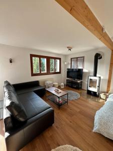 sala de estar con sofá de cuero negro y chimenea en Chalet du Moléson, en Gruyères