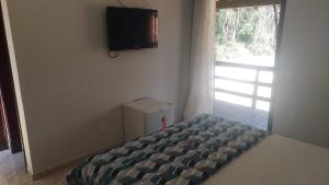 a bedroom with a bed and a television on the wall at Hotel Pousada Recanto das Árvores in Búzios