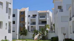 two white apartment buildings with trees in front of them at Beautiful apartment with SEAVIEW Malabata in Tangier