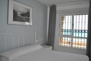 a white bedroom with a bed and a window at Apartamentos la Caracola in Adra