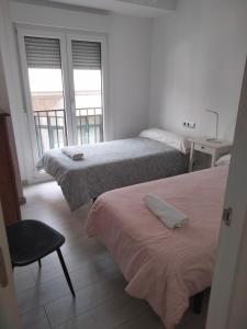 a room with two beds and a chair and two windows at EL RINCON DE LUZ 2 in Padrón