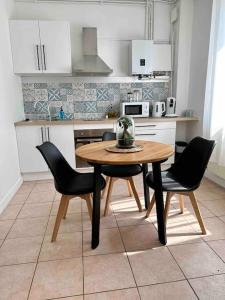 a kitchen with a wooden table and two chairs at Appartement lumineux Parking Privé Gratuit in Bourg-en-Bresse