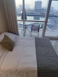a bedroom with a bed and a table and a balcony at Studio in the heart of Sports City -great view & amenities! in Dubai