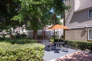 eine Terrasse mit einem Sonnenschirm, Stühlen und einem Tisch in der Unterkunft Residence Inn Orlando Altamonte Springs / Maitland in Orlando