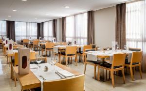 a restaurant with wooden tables and chairs and windows at ALEGRIA Maripins in Malgrat de Mar