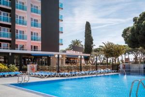 une piscine dans un hôtel avec des chaises et un bâtiment dans l'établissement Hotel Cartago Nova by ALEGRIA, à Malgrat de Mar