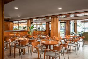 un restaurant avec des tables et des chaises en bois ainsi que des fenêtres dans l'établissement Hotel Cartago Nova by ALEGRIA, à Malgrat de Mar