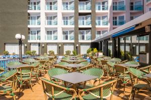 an outdoor patio with tables and chairs and a building at Hotel Cartago Nova by ALEGRIA in Malgrat de Mar