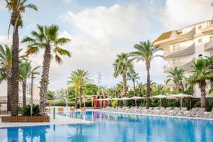 een zwembad in het resort met palmbomen en stoelen bij ALEGRIA Caprici Verd in Santa Susanna