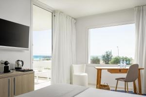 a bedroom with a bed and a desk and a table with a television at ALEGRIA Mar Mediterrania - Adults Only 4*Sup in Santa Susanna