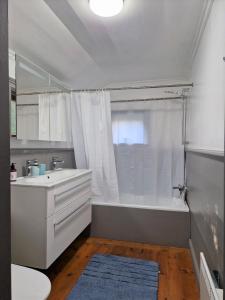 a white bathroom with a tub and a sink at Charmig stuga mitt i naturen! in Upplands-Väsby