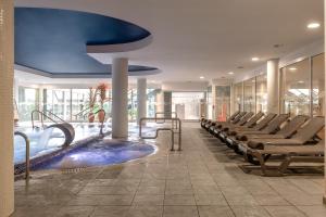 a hotel lobby with a swimming pool and chairs at ALEGRIA Caprici Verd in Santa Susanna