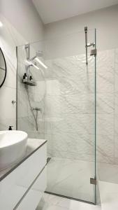 een witte badkamer met een wastafel en een douche bij Linden Apartman 104 - Adults Only in Mosonmagyaróvár