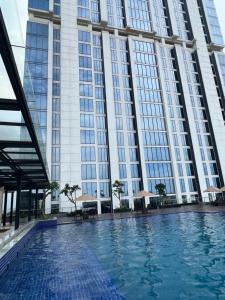 een zwembad voor een hoog gebouw bij Pollux Habibie Studio Batam 53F (Seaview) in Batam Center