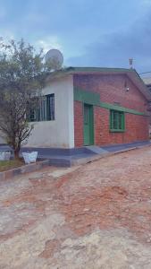 a brick building with green doors and a tree at Hostelito Room in Kigali