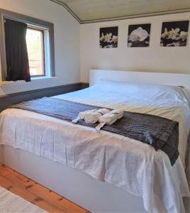 a white bed with two stuffed animals on it at Charmig stuga mitt i naturen! in Upplands-Väsby