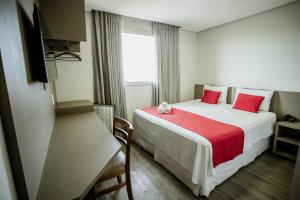 una habitación de hotel con una cama grande con almohadas rojas en Lagoa Flat Hotel, en Lagoa da Prata