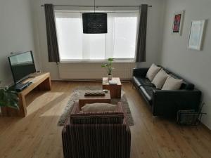 sala de estar con sofá negro y TV en Casa Frida, en Ostende