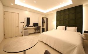 a bedroom with a bed and a desk and a table at Brown Dot Hotel Sinan in Gwangju