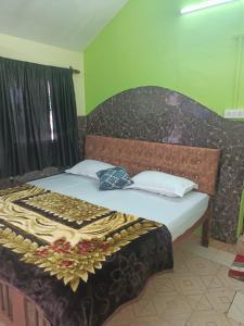 a bed with a wooden headboard and white pillows at Colva Beach Samaira GuestHouse & Apartments in Colva