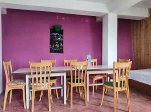 une salle à manger avec des murs violets, une table et des chaises dans l'établissement Kolakham Rai Paul Residency Homestay, à Lava 30 autres photos