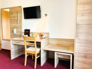 a room with a desk with a chair and a television at Gasthaus und Landhotel Wiedmann in Eresing